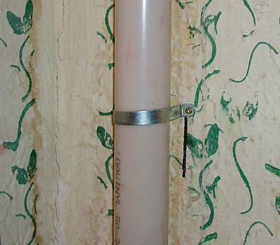 Rura przymocowana do ściany za pomocą metalowej klamry.